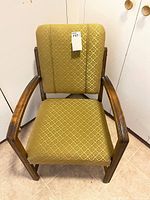 Front view of vintage wooden framed chair upholstered with yellow-green patterned cloth on seat and backrest.