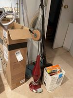 Overall view of vintage floor cleaners, vacuum bags, and accessories packed together, including a boxed item and two floor sweepers