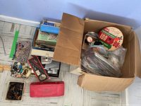 Wide view of box and containers holding assortment of buttons, pins, lace, and ribbons on floor.