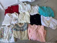 Overview of 10 vintage sweaters in various colors and knit patterns including floral embroidery and pearl beading trims.