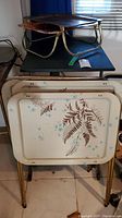 Photo of TV trays and lap trays stacked, showing floral pattern and metal legs.