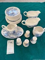 Full set showing stacked medium and small plates, gravy boat, creamer, four salt and pepper shakers, and serving platter beneath items.