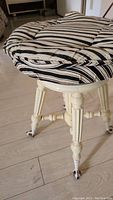 Close-up of the round fabric seat cushion with black and white stripes showing wear and rip along the top edge.