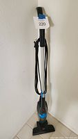 Full front view of the black and blue lightweight Bissell stick vacuum with cord wrapped around the handle.