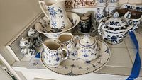 Photo showing Alfred Meakin blue and white pitcher and basin bowl set, sugar bowl, creamer, and platters with blue onion pattern including two small ceramic salt/pepper shakers