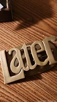 Close view of large brass clip with 'LATER' text.