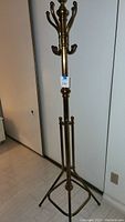 Full view of the tall brass hat tree rack showing its height and tripod-style base.