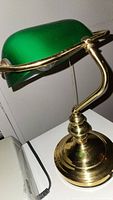 Side view of the bankers lamp showing the green glass shade and brass arm with pull chain.