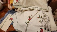 White embroidered linen tablecloth and matching napkins with floral and bird designs on a wooden surface