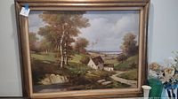 Frontal view of framed landscape oil painting showing trees, house, pathway, and cloudy sky.