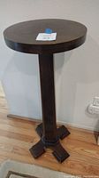 Full view of the wooden plant stand showing round top, pedestal column, and base.