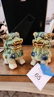 Front view of the pair of ceramic Chinese Guardian Lion (Fu Dog) figurines showing male with teeth and female with closed mouth.