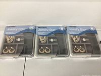Photo showing three sealed packages of Neatnix Jewelry Stax trays, each tray with visible compartments containing jewelry for display purposes.
