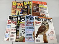 Photo showing a collection of 15 Woodworking magazines from various years with colorful cover images related to woodworking projects and carving.