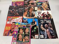 Full view of all 9 WWF wrestling magazines arranged on a white surface showing covers featuring The Rock, Stone Cold Steve Austin, and others