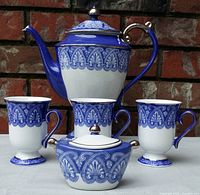 Front view of the complete coffee set: coffee pot, three cups, and sugar bowl all in blue and white with platinum trim against brick background