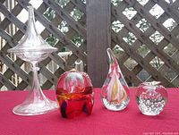 Photo showing all four glass art pieces on red fabric with wooden lattice background.