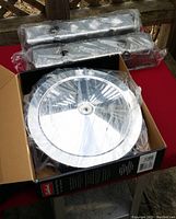 Photo showing 14-inch round chrome air cleaner in box and two wrapped rectangular valve covers behind it on a table.