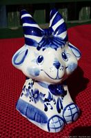 View of blue and white ceramic goat figurine showing front and angled side, highlighting striped horns and floral patterns.