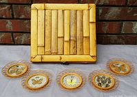 Top view of square bamboo curio box and five rattan coasters featuring preserved butterflies.
