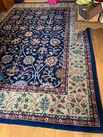 Full view of navy-based area rug on hardwood floor, showing overall floral pattern and condition