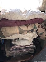 Stack of knitted blankets, quilts, and pillows on a rocking chair showing knit and patchwork fabrics.