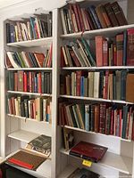 Two white shelves filled with various religious and reference books, showing a mix of colors and wear.