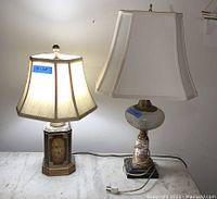 Two table lamps and one floor lamp, lamp cords visible, lamp on left has a hexagonal decorative metal base with floral design, lampshades are cream colored fabric, untested condition.