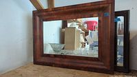 Full view of larger wood framed mirror showing rectangular shape and wood grain finish with scratches.