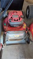 Front view of red Troy-Bilt lawn mower with black handlebar and engine cover showing wear and dust