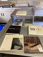 Five architecture coffee table books arranged on a grey counter, titles including Richard Meier Architect, Architecture Transformed, 10x10, Wall by Andy Goldsworthy, and Torri.
