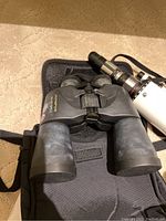 Olympus black binoculars on soft case, showing body and lenses from top view.