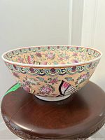 Side view of ceramic bowl showing colorful butterfly and floral patterns against a peach background.