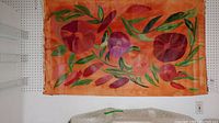 Abstract floral canvas painting with orange, red, and green colors, displaying wear and tack holes