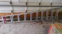 Full side view of aluminum step ladder showing length and structure lying on floor.