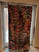 Full view of the hanging patchwork quilt showing its size, shape, and overall color pattern.