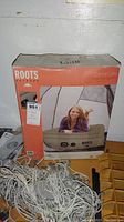 Photo of the original retail box showing the front of the Roots Outdoor Canoe Lake Double High Insta Bed with a person lying on the mattress.