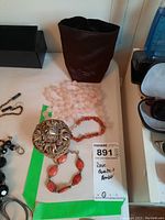 Photo of all items in the lot including the jewelry box with lid, rose quartz necklace, amber bracelet, and sterling silver bracelet.