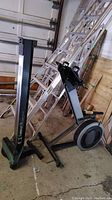 Flywheel assembly with seat base and footrests next to upright monorail section in garage setting