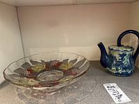 Photo showing the teapot and the colored pressed glass bowl together on a shelf.
