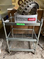 Frontal view of the metal wire rack with three shelves showing the overall structure and wear.