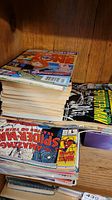 Stack of comic books showing varied colorful covers and partially visible titles including some signed Spider-Man comics and Archie comics.