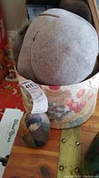 Two grey felt hats inside a floral patterned hat box with a hand painted decorative stone nearby