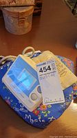 Photo of Omron digital blood pressure monitor accompanied by the fabric arm cuff and blue heating pad on a table.