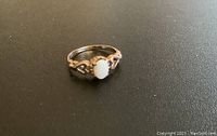 Front close-up of the 10K gold pinky ring with central opal stone on a dark background.