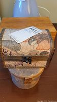 Front view of the rectangular chest with world map design atop the round box.