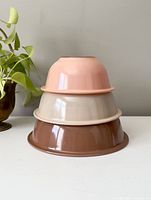 Stacked set of three vintage Pyrex nesting mixing bowls in brown, cream and pink colors.