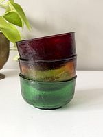 Stacked view of the three glass bowls showing amber, red, and green colors and textured glass surfaces.