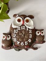 Front view of vintage chalkware owl clock, showing large owl with clock face and two smaller owls on a branch.