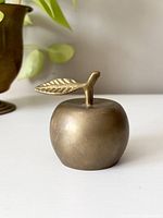 Front view of the vintage brass apple bell showing its smooth surface and leaf detail on top.